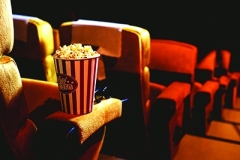 Popcorn and 3d glasses on yellow armchair in cinema with copy space.